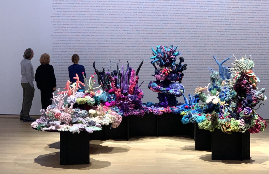 large gallery installation of crochet coral reefs with people looking